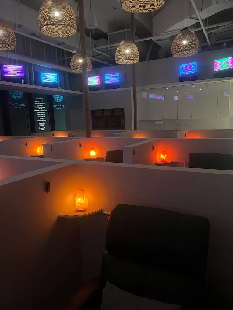 A soothing gut health relaxation lounge with softly illuminated cubicles, each featuring a salt lamp to promote a calming environment and comfortable recliner chairs for deep relaxation. Educational displays and visual guides on the walls share inspiring insights about digestion, microbiome balance, and holistic wellness.